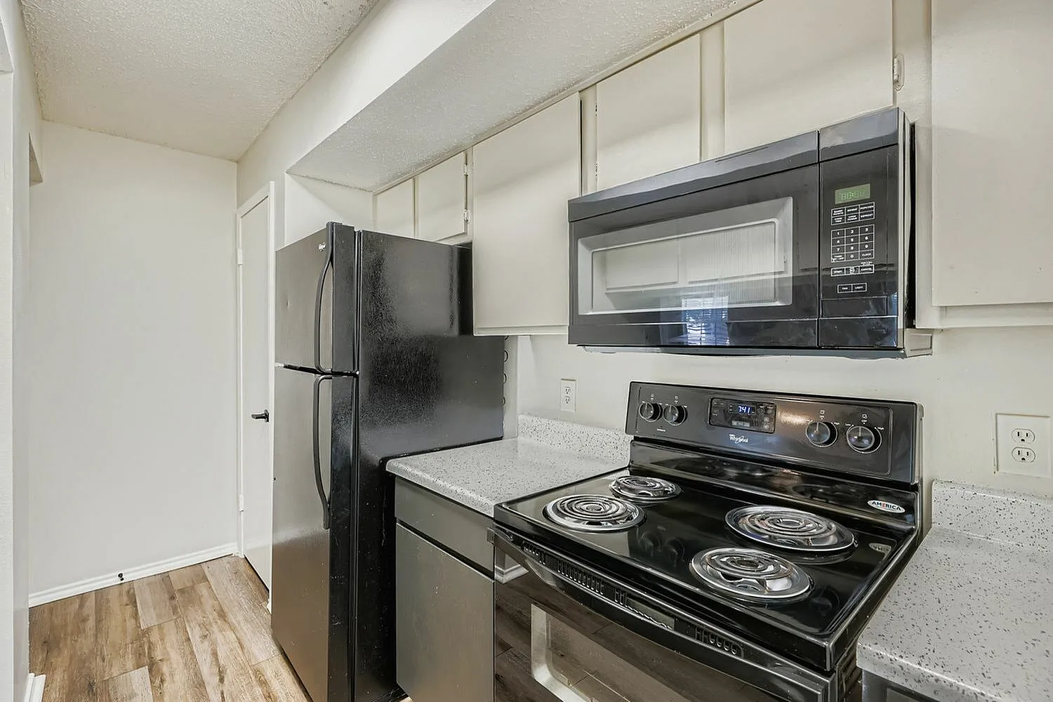 Kitchen, white cabinetry, quartz countertops, black stainless appliances, wood-style plank flooring