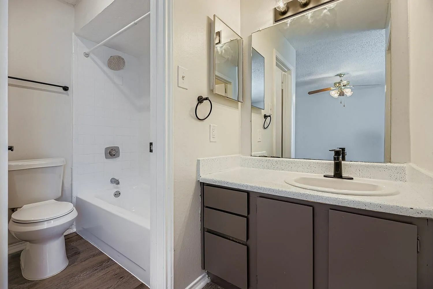 Primary bathroom, dark wood cabinetry, white quartz countertops, large mirror, tile shower