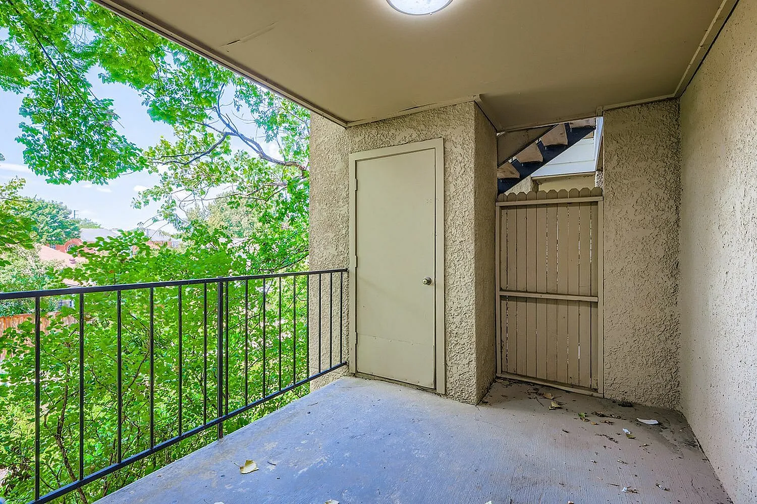 Balcony, metal railing, beige textured walls, white door, exterior storage gate