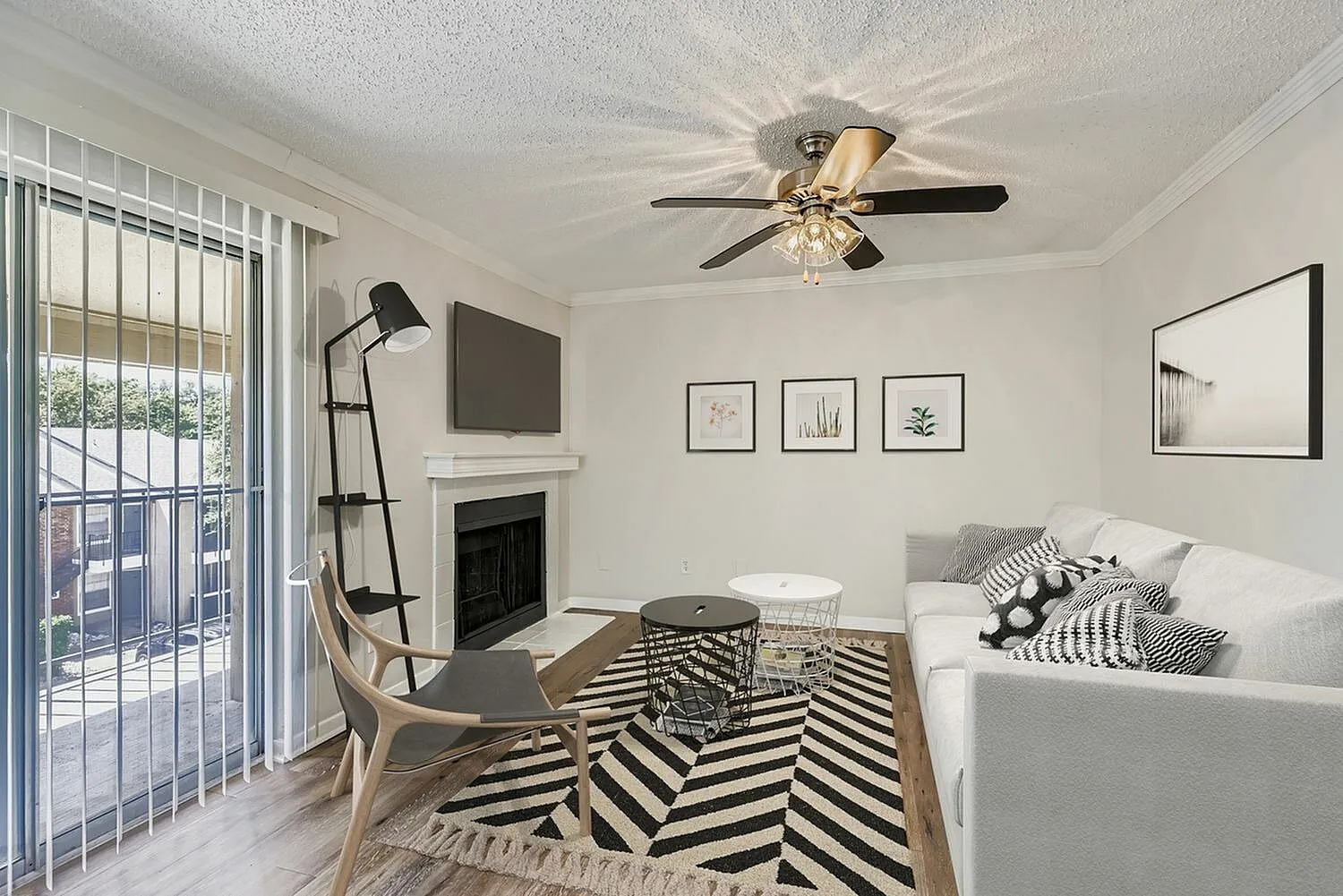 Living room, wood-style plank flooring, geometric area rug, fireplace, ceiling fan
