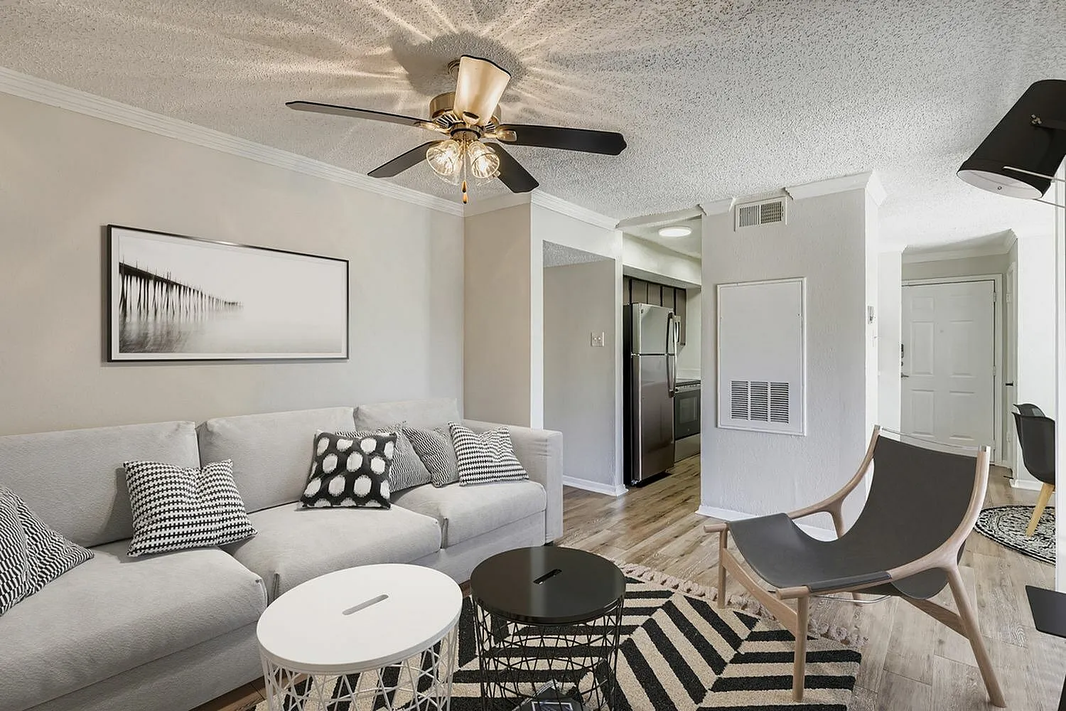 Living room with wood-style plank flooring, ceiling fan, gray sofa, striped area rug