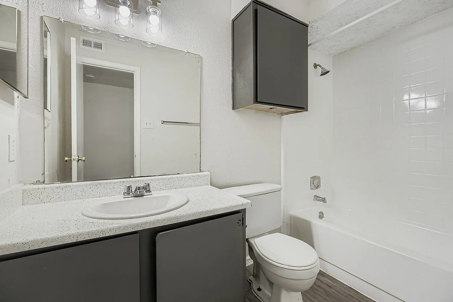 Bathroom, white round sink, dark vanity cabinetry, quartz countertops, white subway tile shower surround