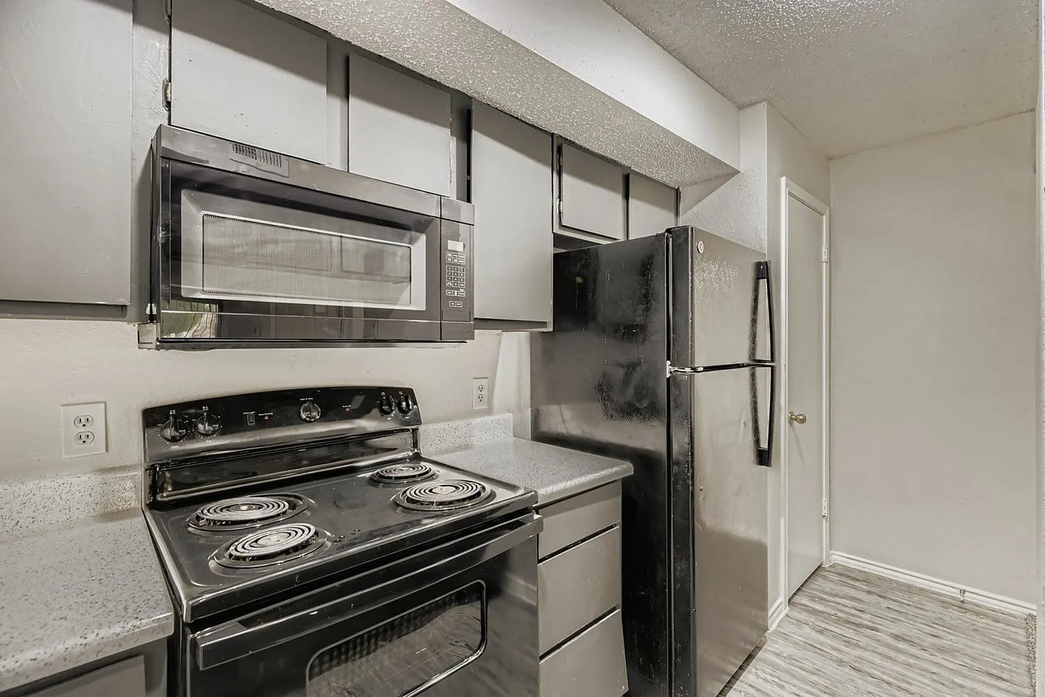Kitchen, black coil-top range, gray countertops, stainless microwave, wood-style plank flooring