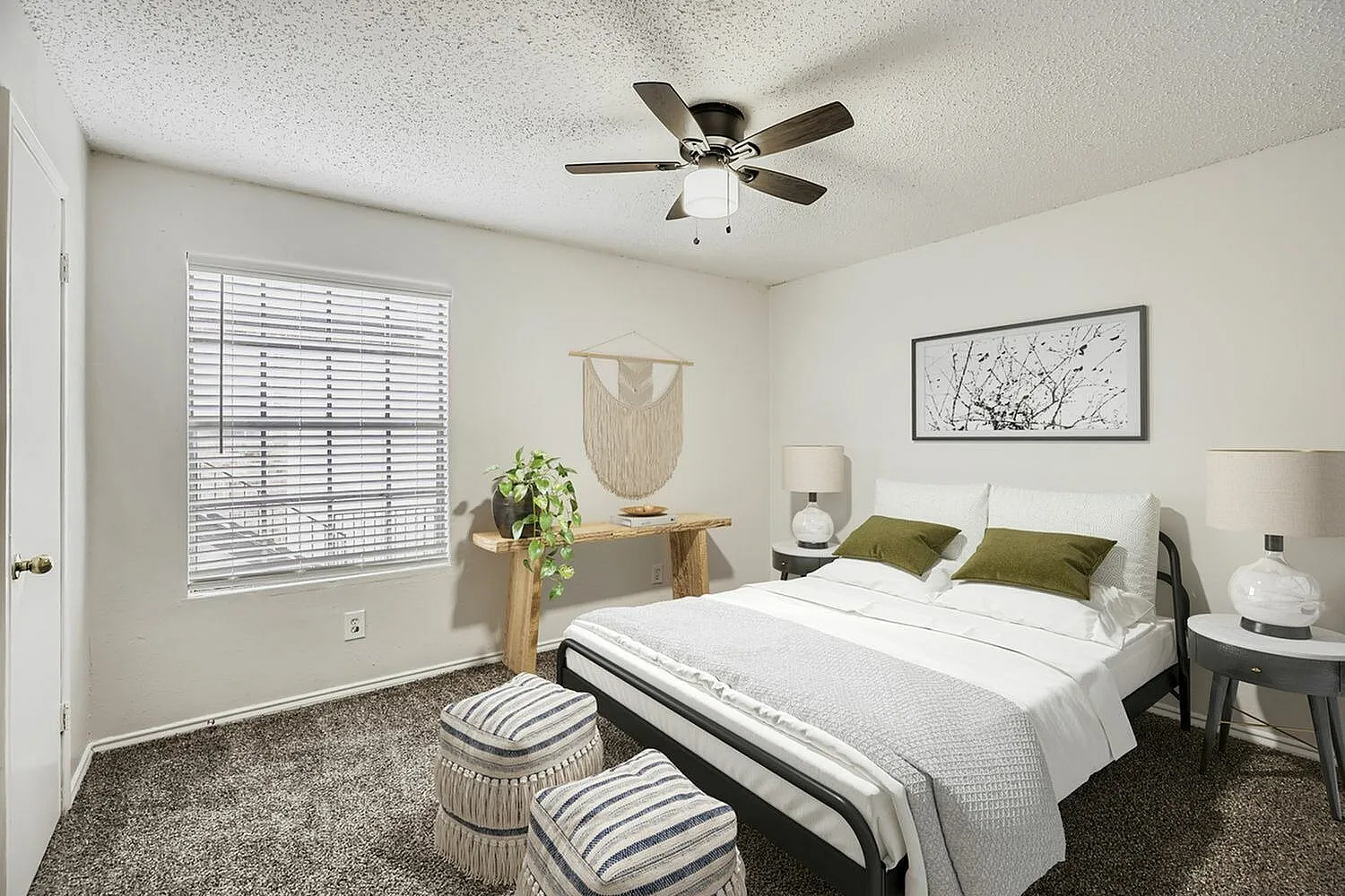 Primary bedroom, dark wood-style plank flooring, ceiling fan, white bedding with green pillows