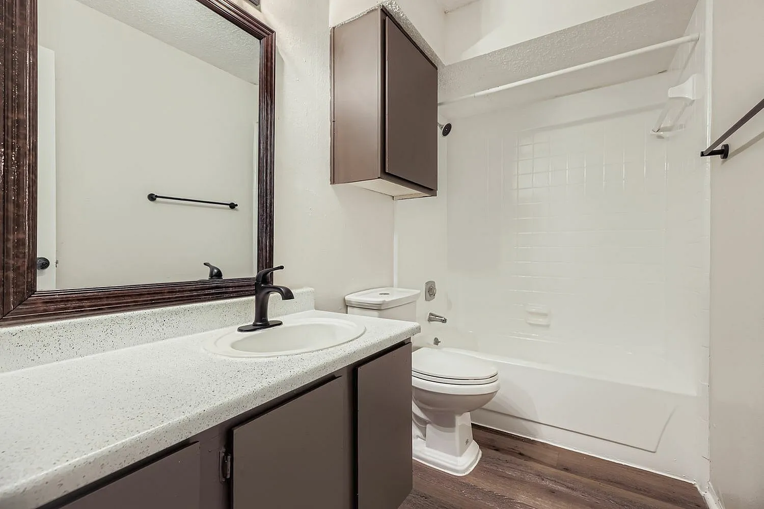 Bathroom, quartz countertop, dark wood vanity, large mirror, white subway tile, toilet, bathtub-shower combo