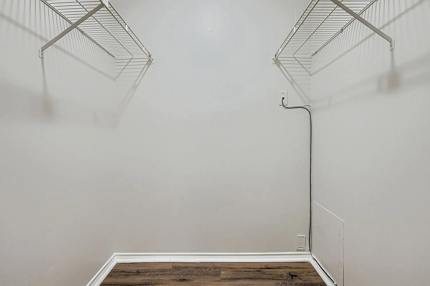 Closet, wood-style plank flooring, white walls, metal shelving units, wall-mounted rod