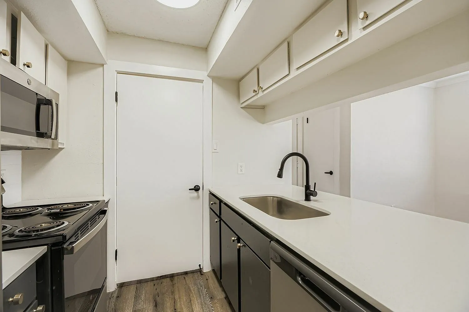 Kitchen, white shaker cabinetry, quartz countertops, stainless appliances, wood-style plank flooring