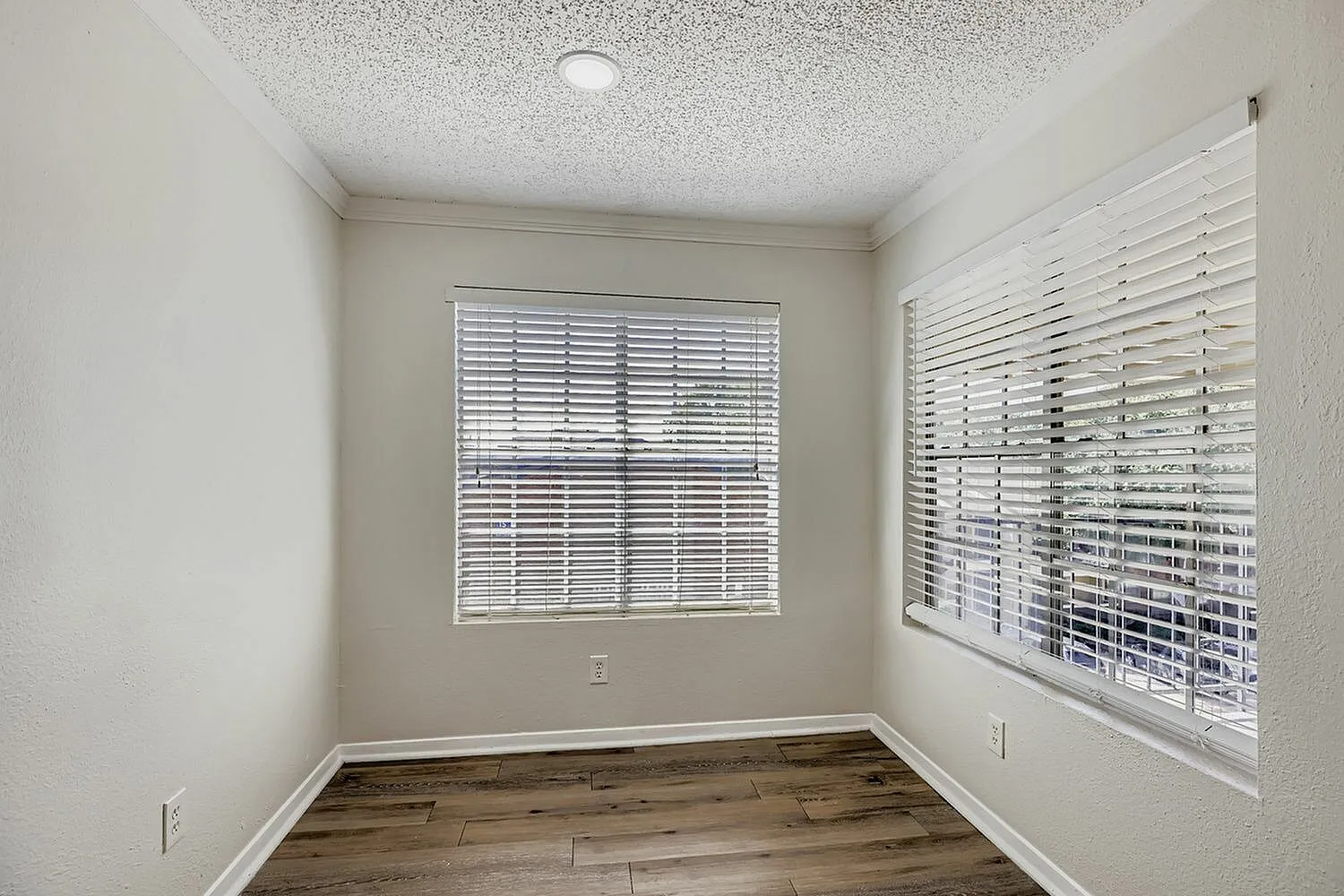 Bedroom, wood-style plank flooring, white plantation shutters, textured ceiling
