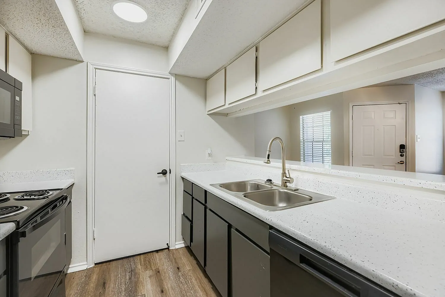 Kitchen, dark cabinetry, white quartz countertops, stainless appliances, wood-style plank flooring