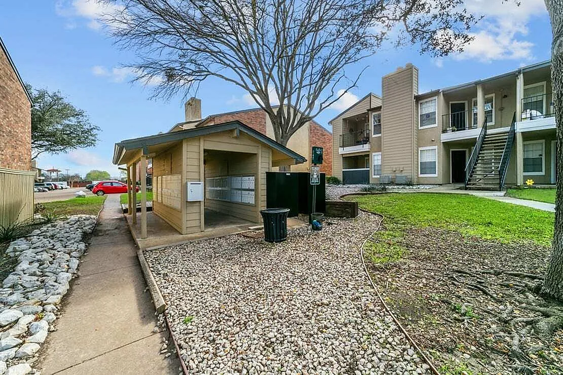 Community courtyard, paved pathways, gravel landscaping, bare tree, adjacent apartment building