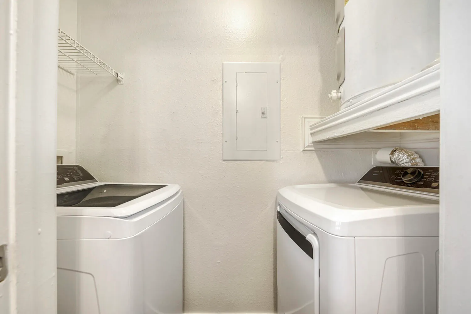 Laundry room, white front-load washer and dryer, white walls, built-in shelving
