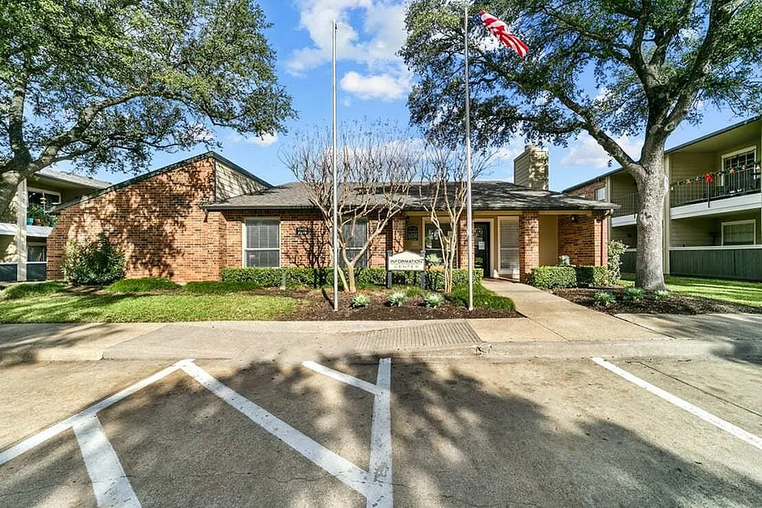 Brick building exterior, manicured lawn, mature trees, entry walkway, Garland TX
