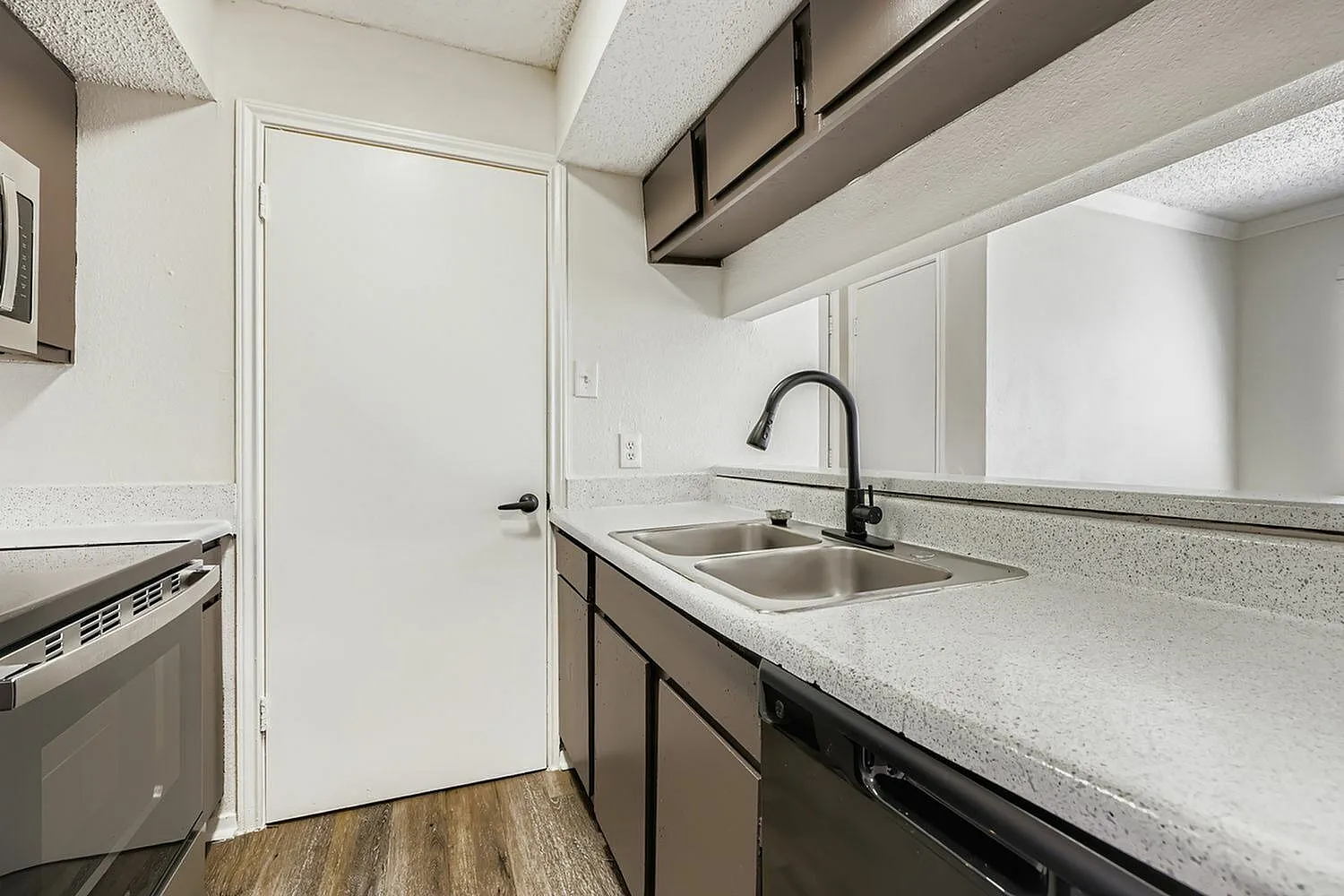 Kitchen, quartz countertops, stainless sink with black faucet, dark cabinetry, wood-style plank flooring
