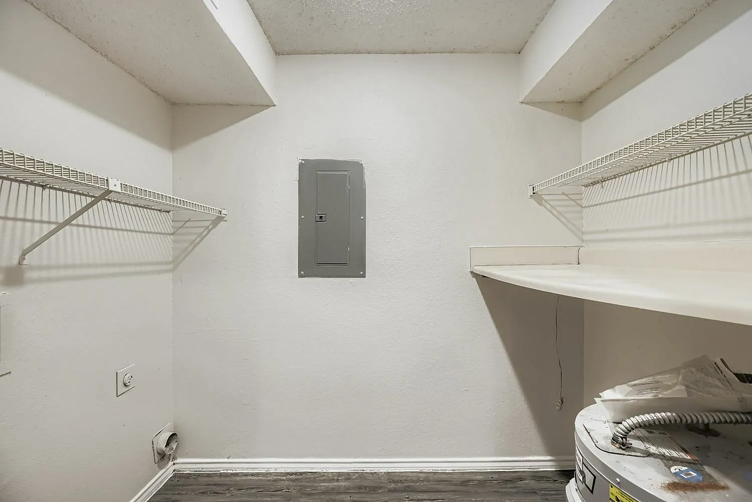 Walk-in closet, wire shelving, white walls, wood-style plank flooring, electrical outlet