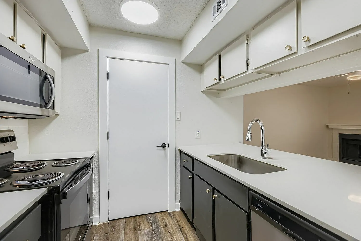 Kitchen, stainless steel appliances, quartz countertops, dark cabinetry, wood-style plank flooring