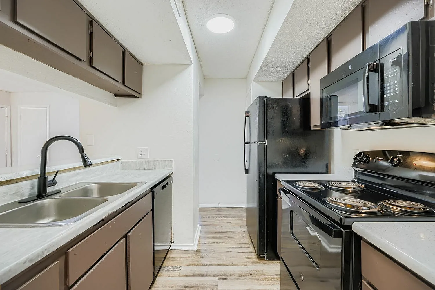 Kitchen, wood-style plank flooring, quartz countertops, stainless appliances, black cabinetry