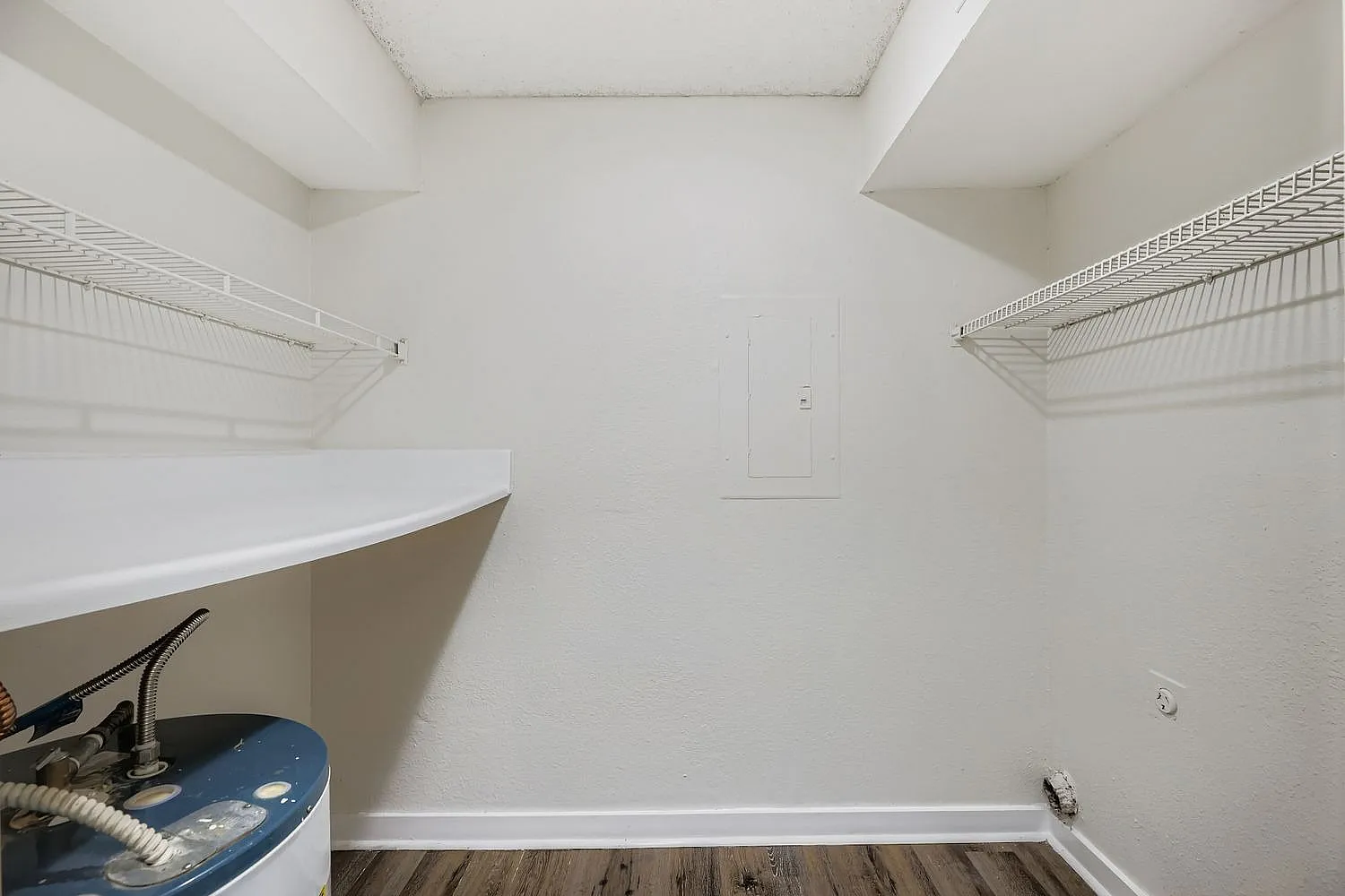 Walk-in closet, wire shelving, wood-style plank flooring, white walls, ceiling lighting