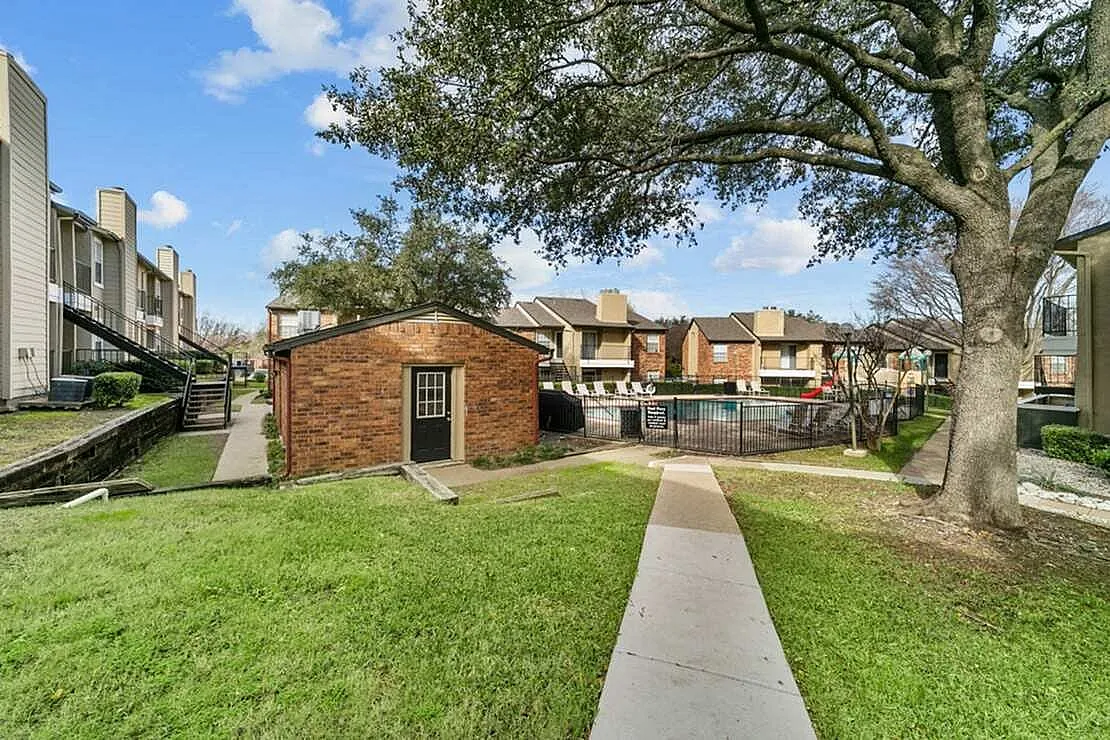 Courtyard with brick building, green lawn, mature tree, concrete walkway, residential units