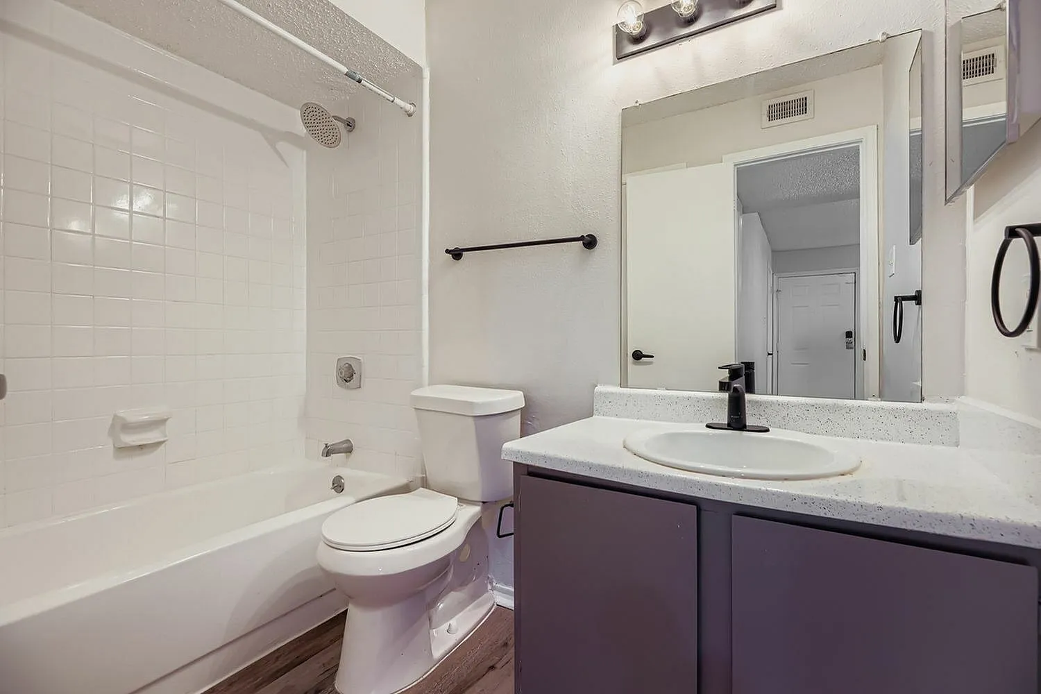 Primary bathroom, dark cabinetry, white quartz countertops, white tile shower surround