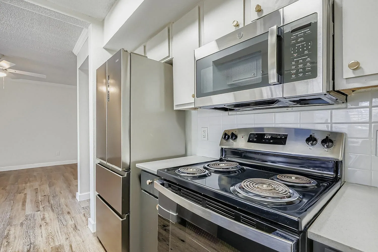 Kitchen, white shaker cabinetry, quartz countertops, stainless steel electric range, stainless microwave, wood-style plank flooring