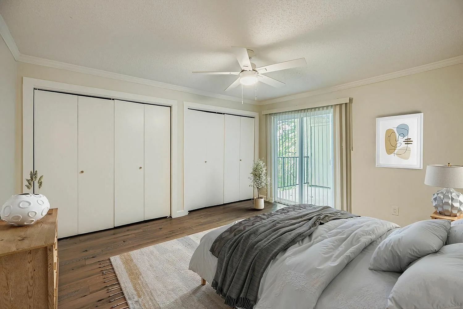 Primary bedroom, wood-style plank flooring, built-in closets, ceiling fan, glass doors