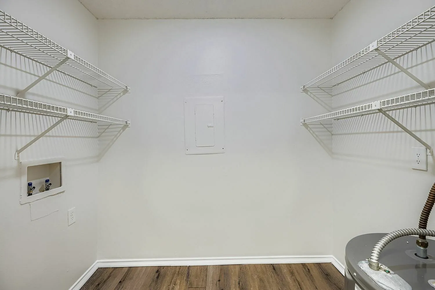 Laundry room, wire shelving, wood-style plank flooring, white walls, electrical outlet