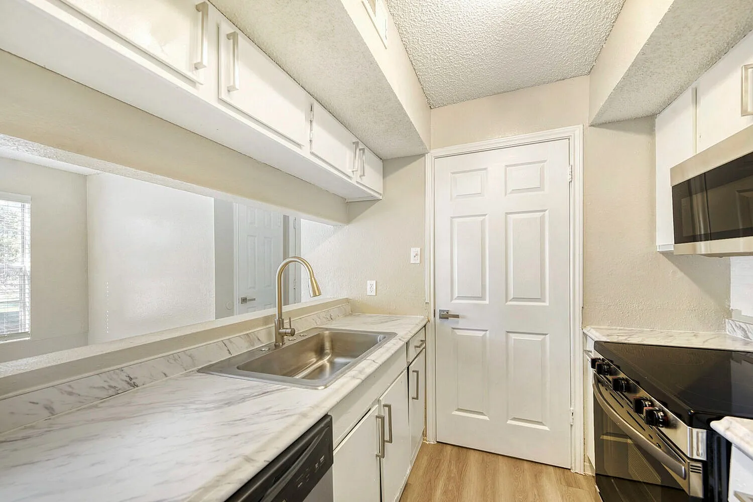 Kitchen, marble countertops, white cabinetry, stainless appliances, wood-style plank flooring