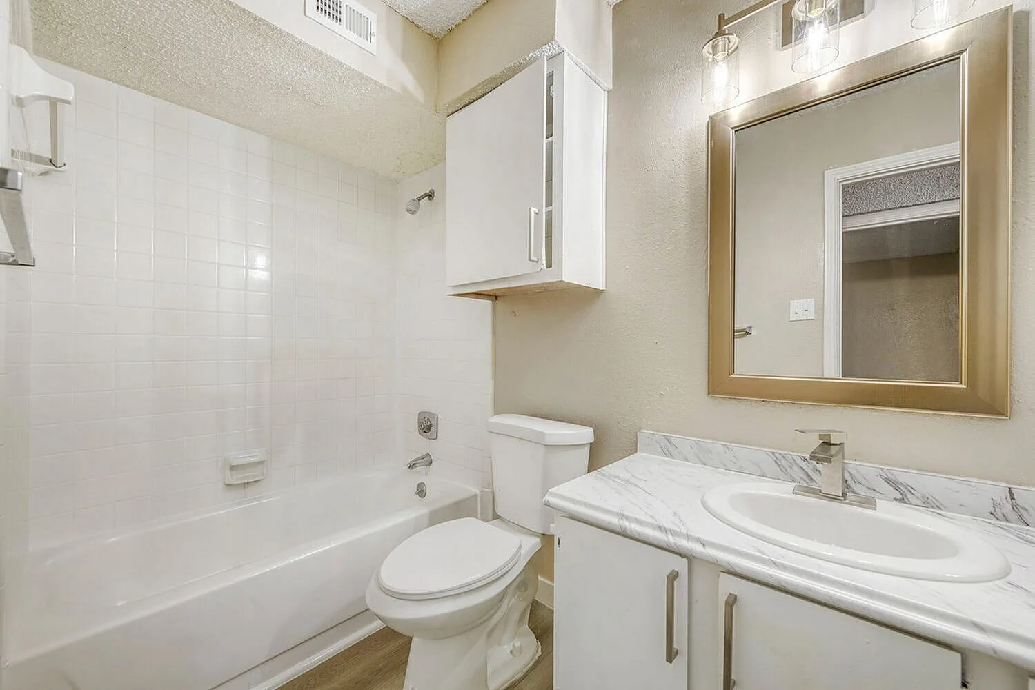 Bathroom, white vanity with marble countertop, framed mirror, white subway tile shower surround
