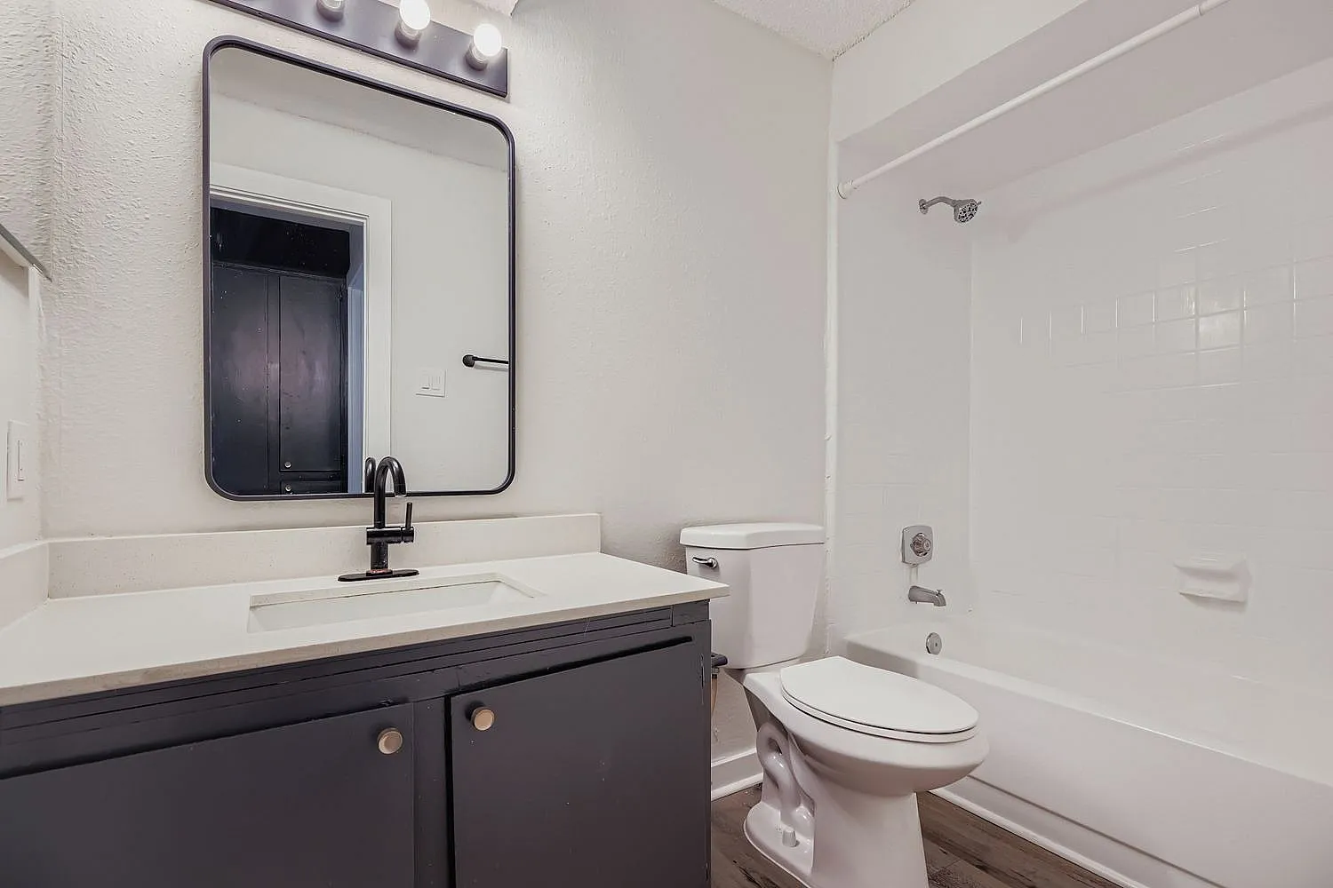 Bathroom, dark wood cabinetry, white quartz countertop, framed mirror, toilet, shower enclosure