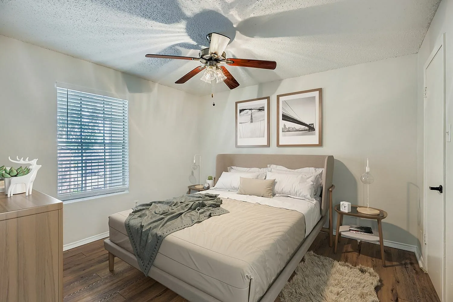Primary bedroom, wood-style plank flooring, ceiling fan, framed wall art
