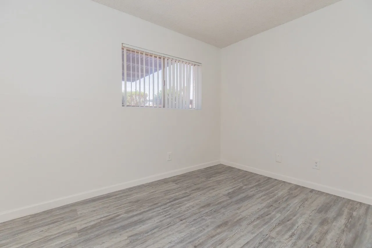 Bedroom, wood-style plank flooring, vertical blinds, white walls