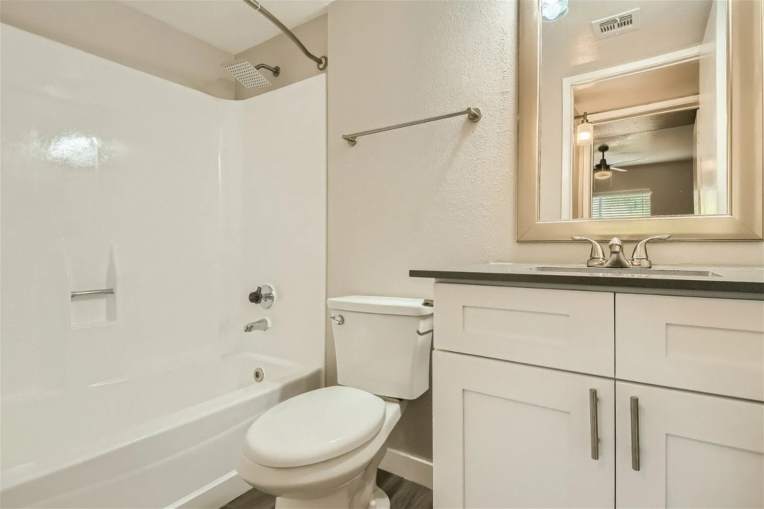 Bathroom, white cabinetry, black countertop, framed mirror, white tile surround
