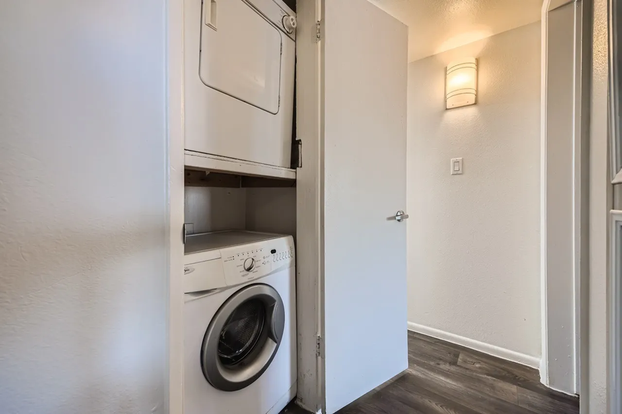 Laundry room, stacked washer dryer, white appliances, wood-style plank flooring