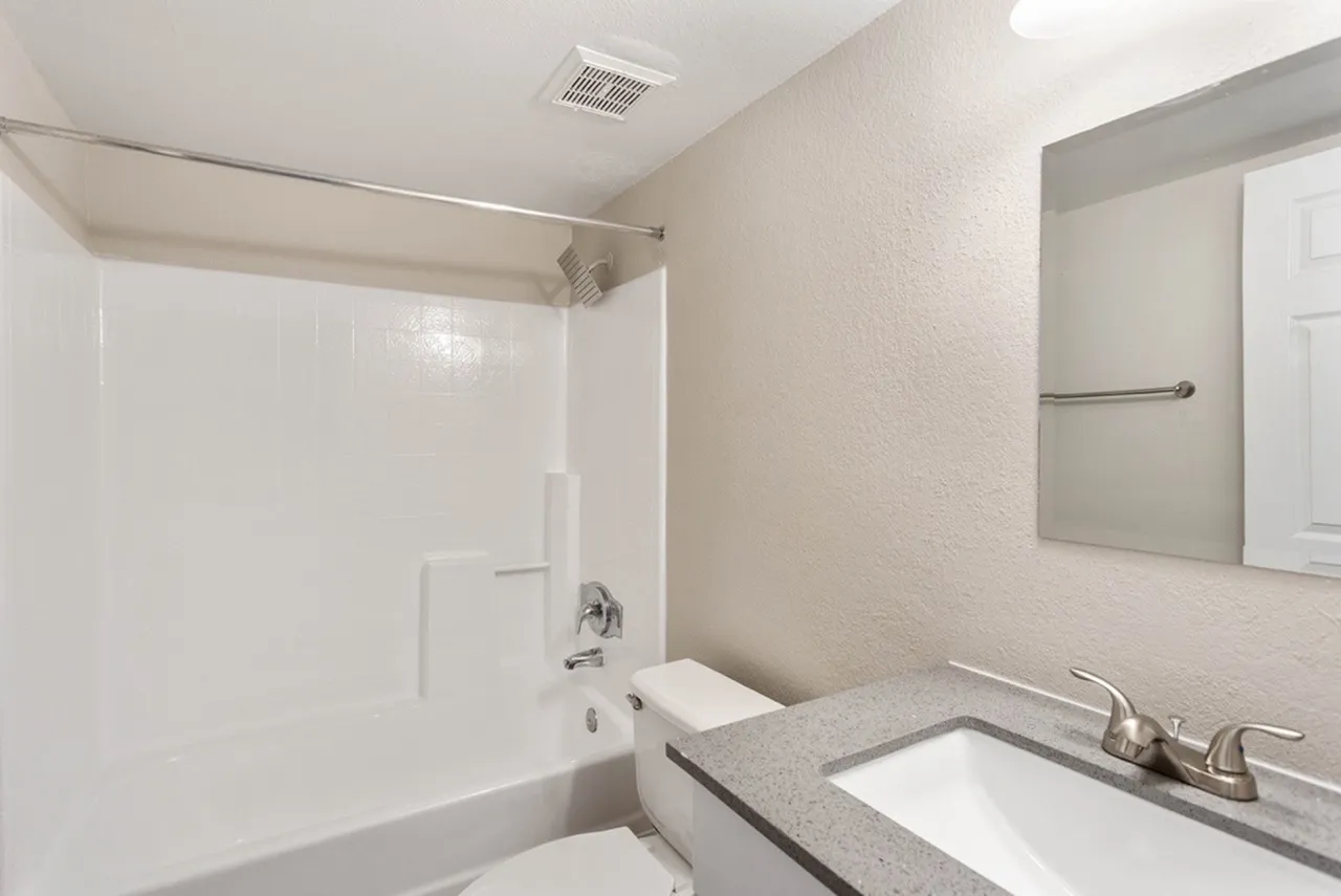 Bathroom, gray quartz countertop, white vessel sink, mirror with towel bar, white shower surround