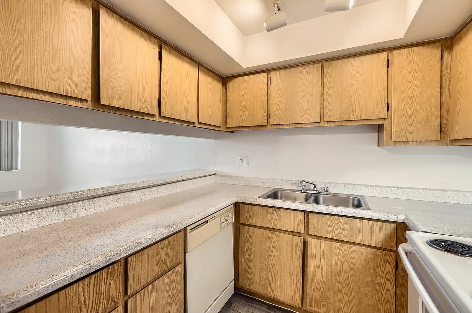 Kitchen, oak cabinetry, speckled countertops, white appliances, white backsplash