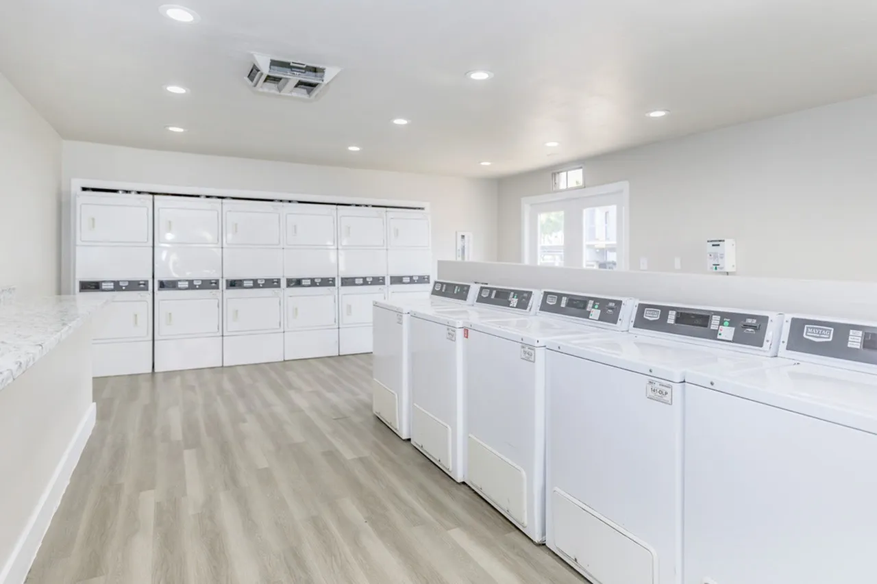 Laundry room, white front-load washers and dryers, wood-style plank flooring, recessed lighting