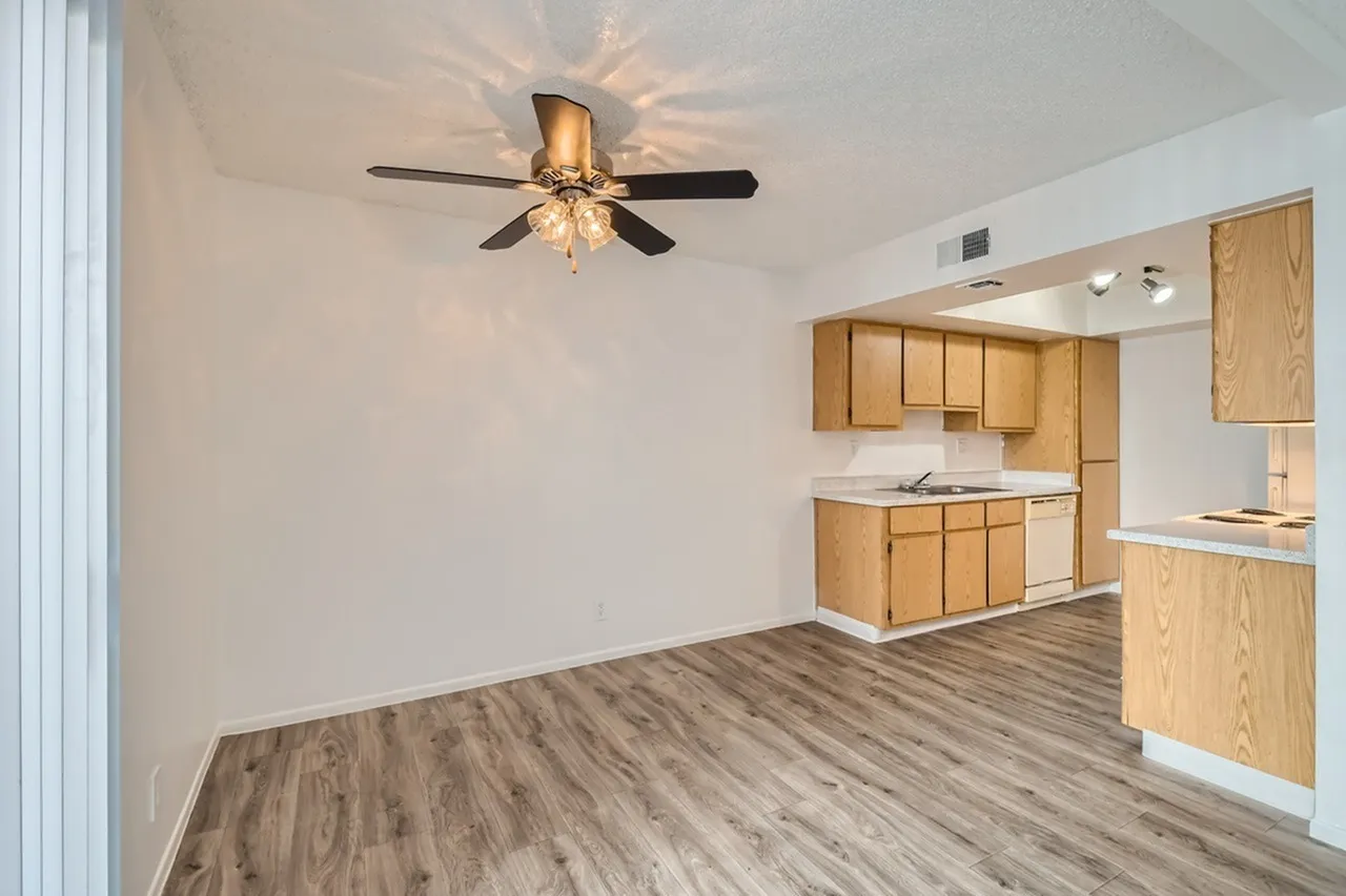 Kitchen and living room, wood cabinetry, wood-style plank flooring, ceiling fan with light