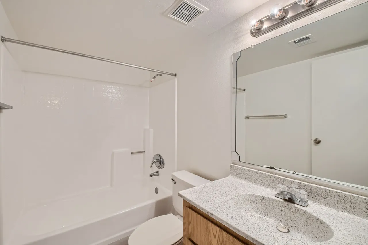 Primary bathroom, dual-sink vanity, quartz countertops, wood cabinetry, large mirror, lighting fixture