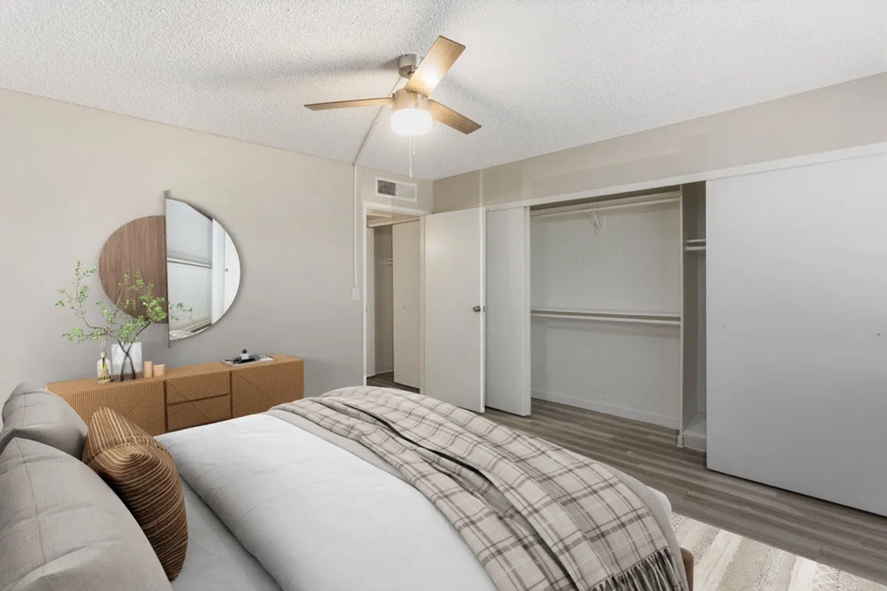 Primary bedroom, wood dresser with round mirror, wood-style plank flooring, ceiling fan