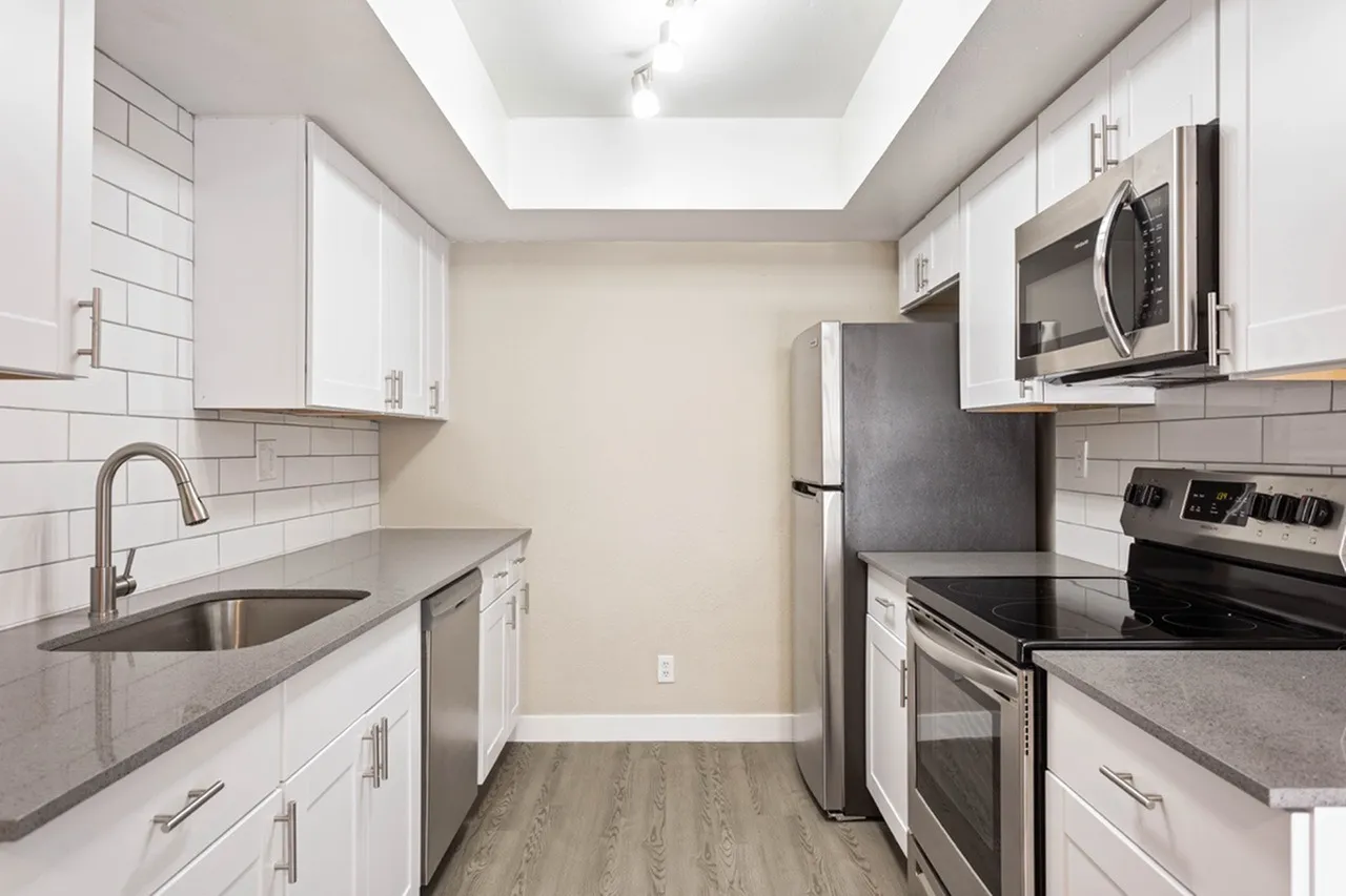 Kitchen, white shaker cabinetry, gray quartz countertops, stainless steel appliances, subway tile backsplash, wood-style plank flooring