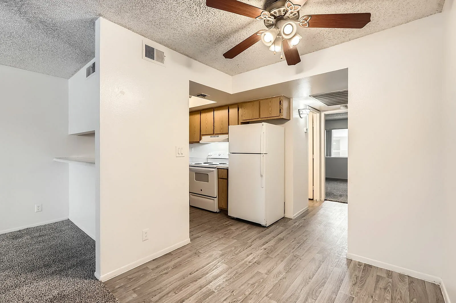Kitchen, wood cabinetry, stainless steel appliances, white refrigerator, wood-style plank flooring, ceiling fan