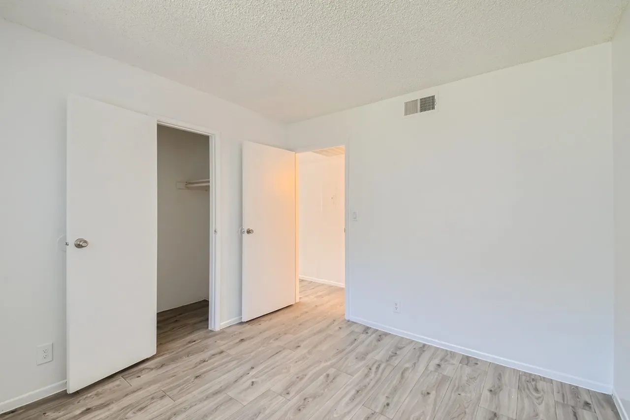 Bedroom, wood-style plank flooring, open closet, ensuite access, white walls