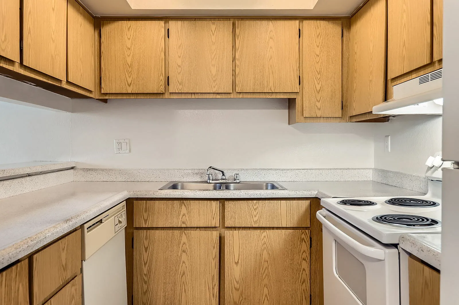 Kitchen, wood cabinetry, white countertops, white electric range, stainless sink