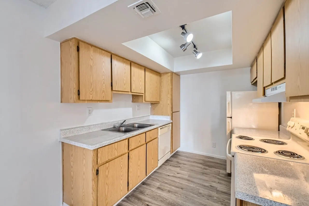 Kitchen, wood cabinetry, white countertops, white appliances, wood-style plank flooring