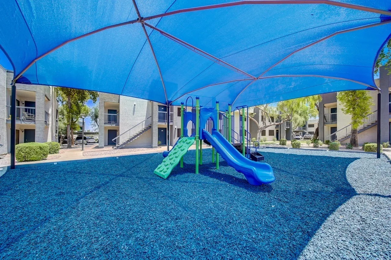 Playground with blue shade structure, green and blue slides, synthetic turf, Phoenix AZ