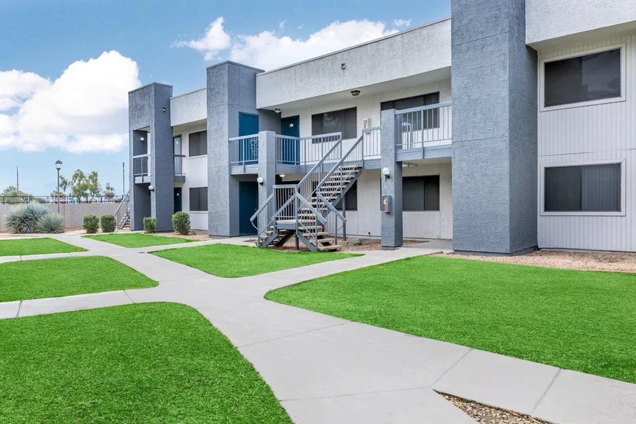 Residential building, multi-story concrete facade, metal railings, manicured lawn, concrete walkways