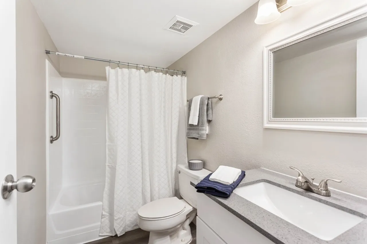 Bathroom, white vanity, quartz countertop, chrome faucet, framed mirror