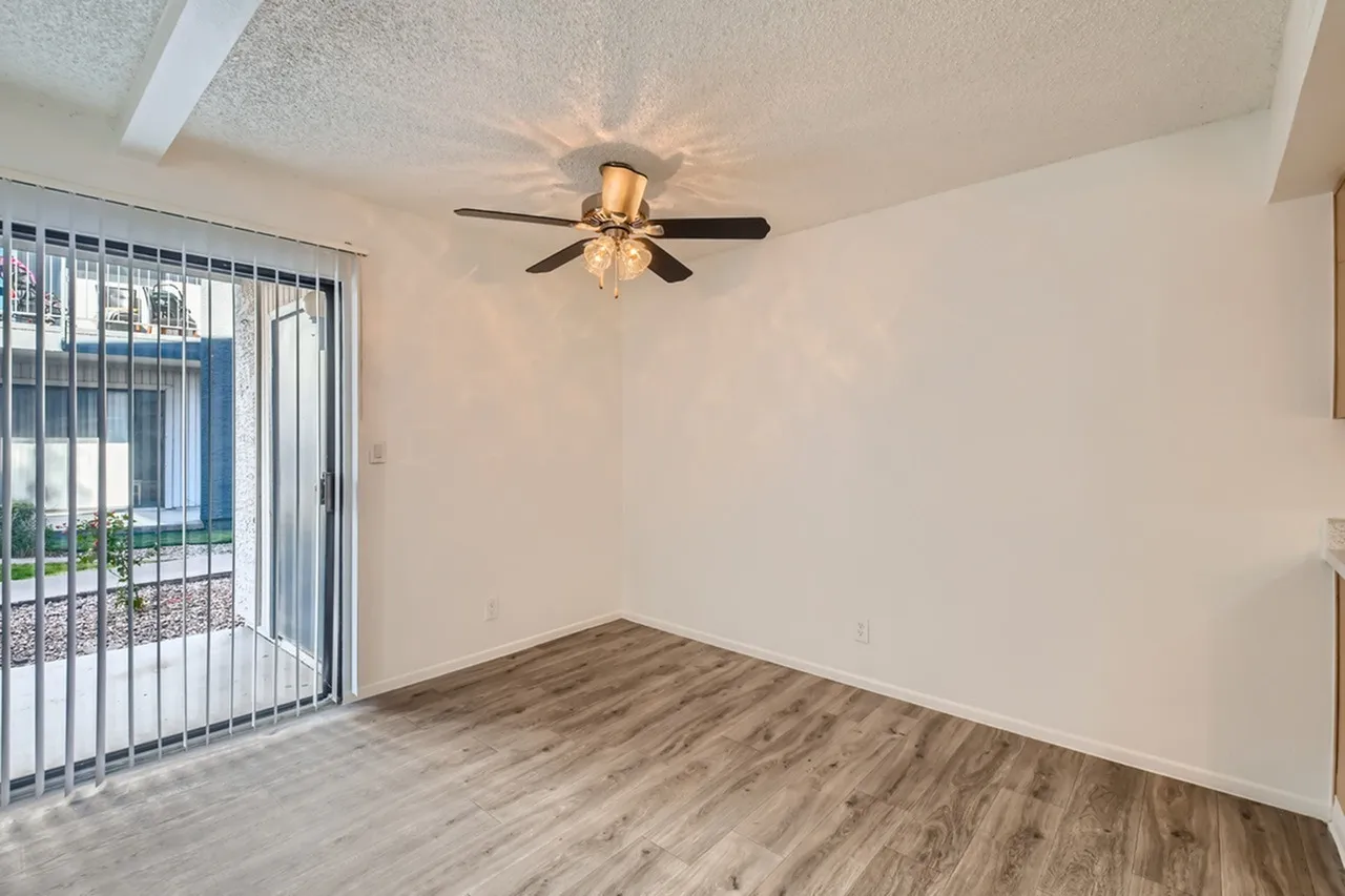 Bedroom, wood-style plank flooring, ceiling fan, vertical blinds, door to patio