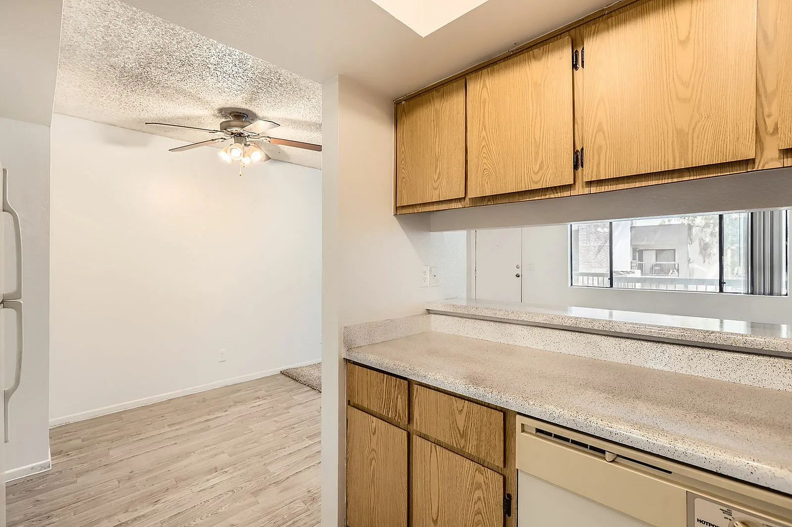 Kitchen with oak cabinetry, light countertops, window view, wood-style plank flooring, ceiling fan