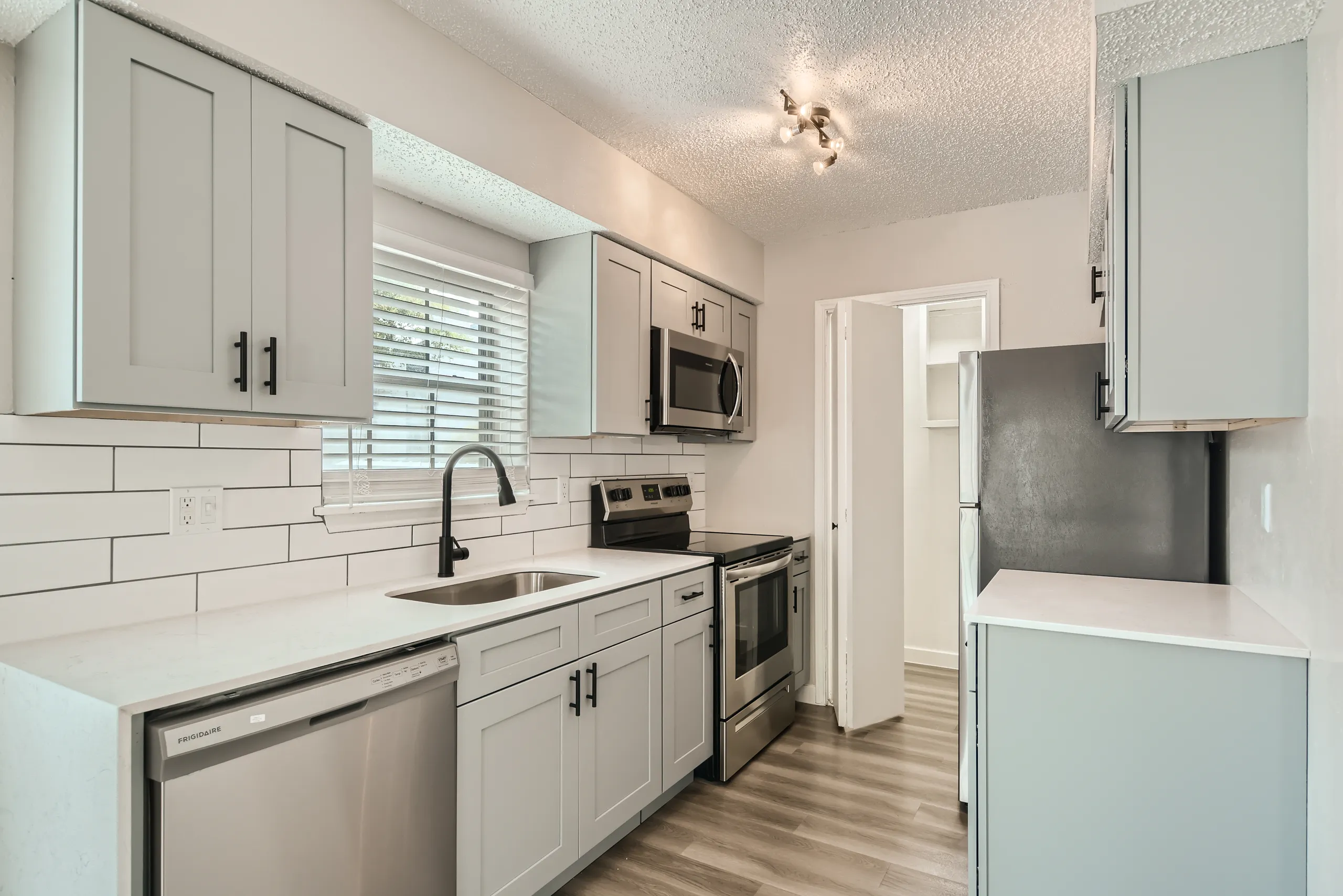 Kitchen with gray shaker cabinets, subway tile, and stainless steel appliances